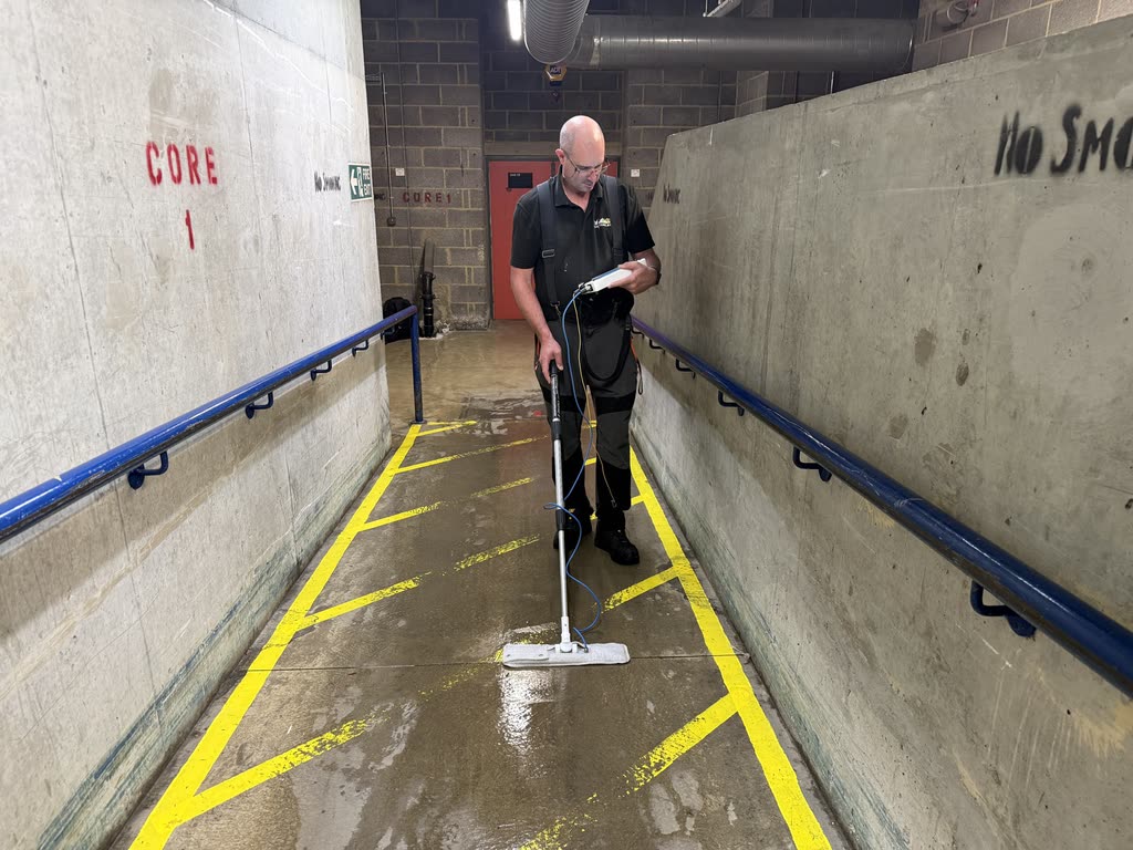 A Trace Surveys surveyor investigating a wet concrete ramp with a floor scanning instrument.